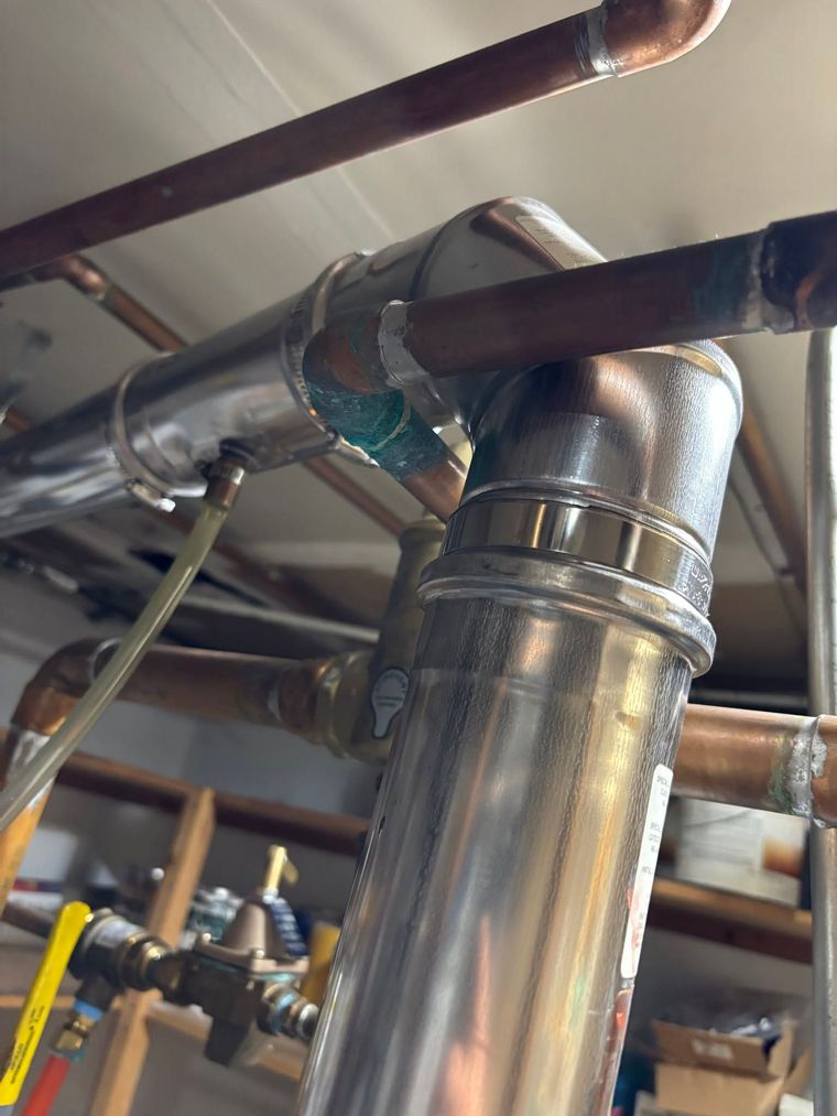 Close-up of shiny metal HVAC ductwork and pipes in a basement ceiling