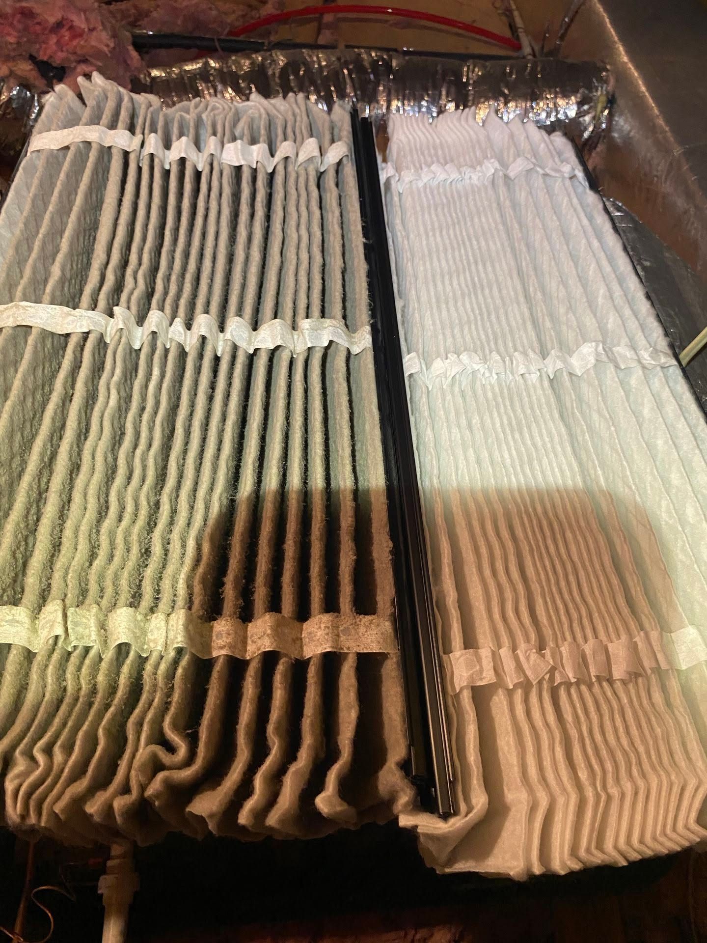 Rows of hanging pleated window blinds in beige, white, and dark gray stacked side by side. Rows of hanging pleated window blinds in beige, white, and dark gray stacked side by side.
