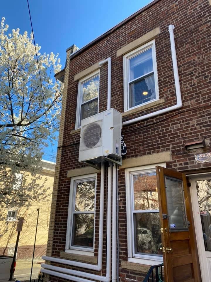Brick townhouse exterior with a wall-mounted air conditioner and open wooden door