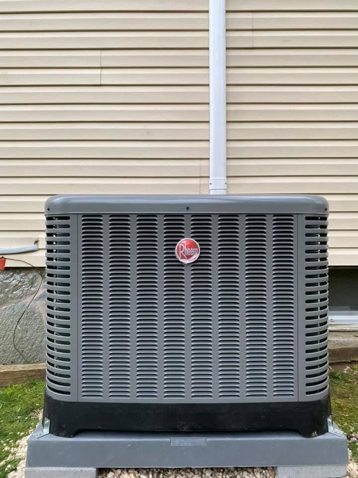 Outdoor air conditioner unit in front of beige siding with a white vent pipe above it. Outdoor air conditioner unit in front of beige siding with a white vent pipe above it.