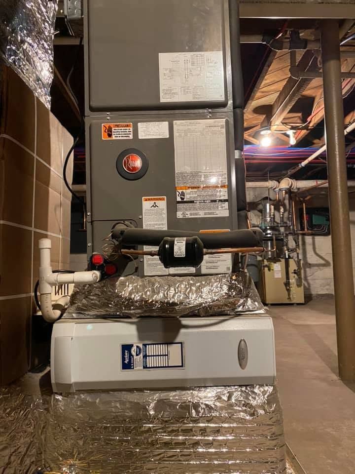 Furnace unit wrapped in foil insulation, installed in a basement or utility room.