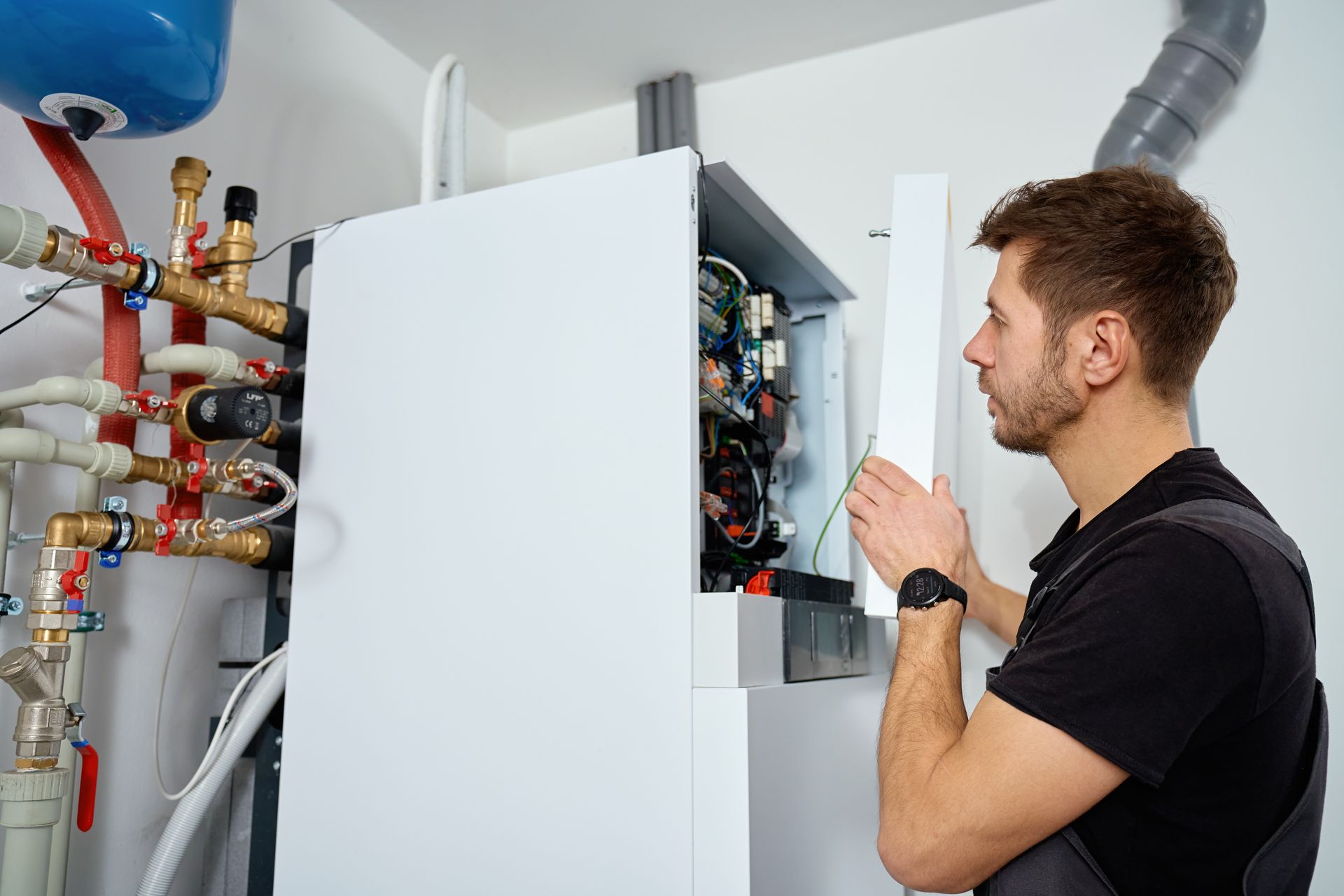 Technician inspecting and servicing a wall-mounted boiler system. Technician inspecting and servicing a wall-mounted boiler system.