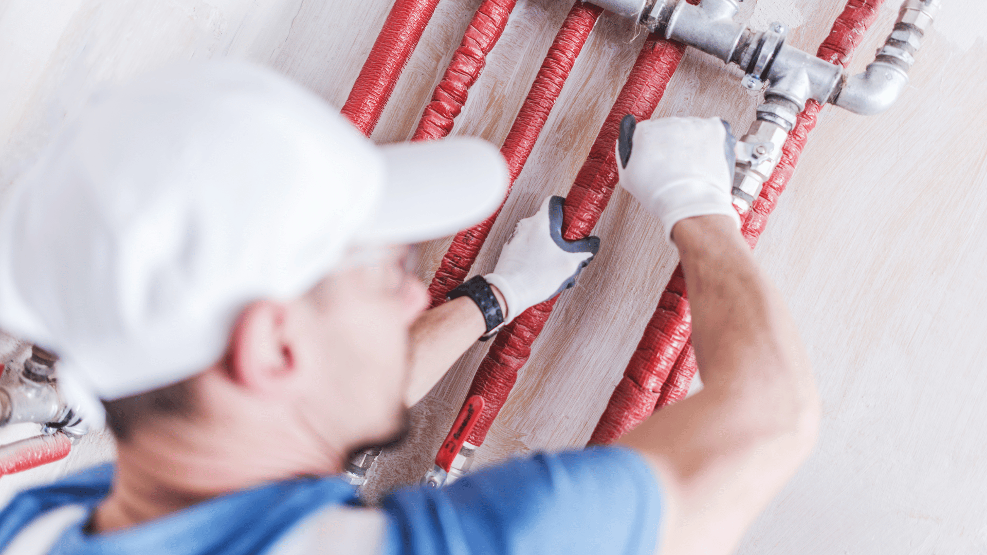 A man is working on a pipe on a wall.