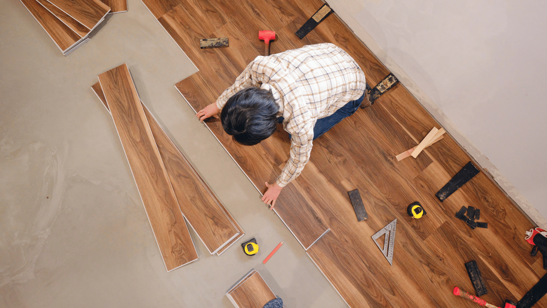 A man is installing a wooden floor in a room.