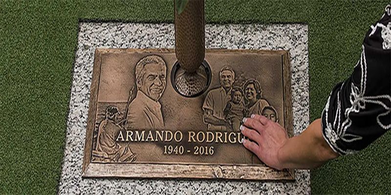 Flat copper grave maker with vase and persons hand on grave marker remembering their loved one
