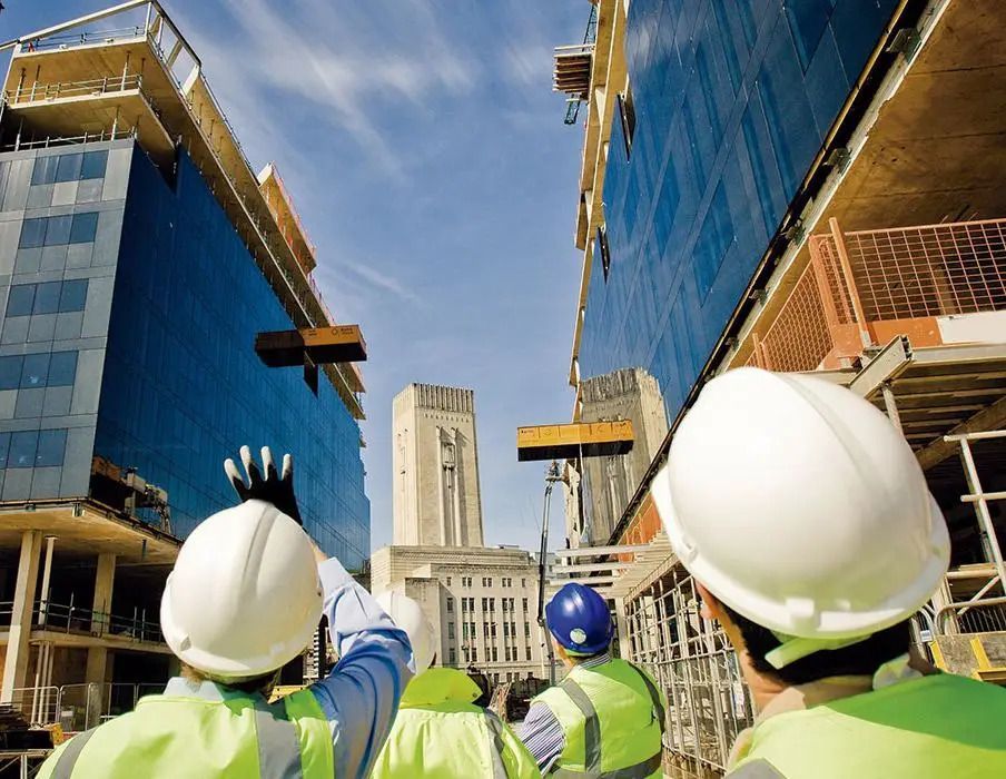 A group of construction workers are looking up at a building under construction
