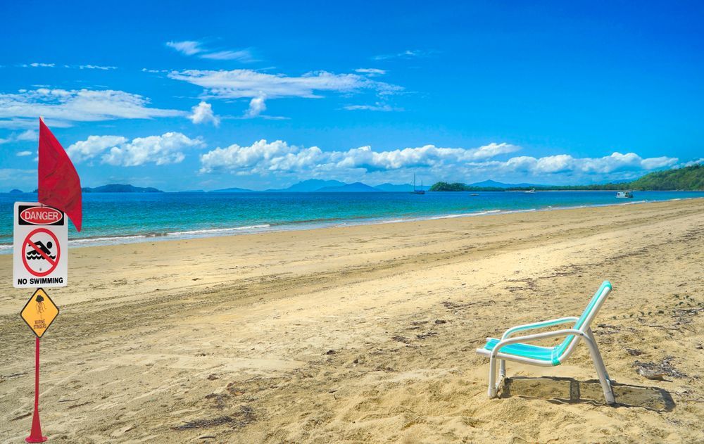 Red Flag and Sign on a Beach Warn of Danger — FNQ Smoke Alarms & Maintenance in Mission Beach, QLD