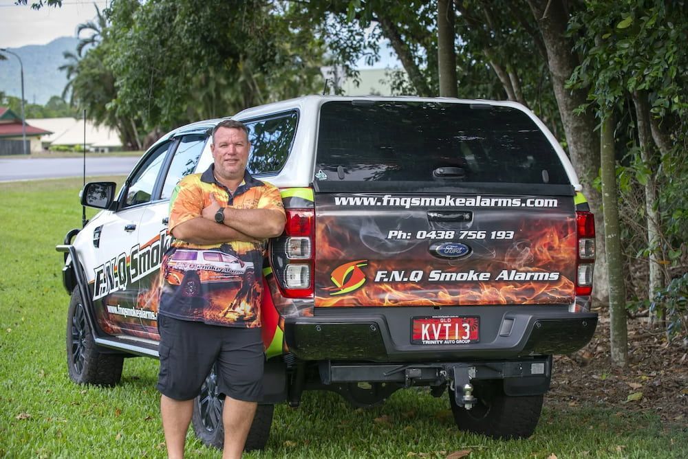Two White Smoke Detectors, a Multimeter, and Coiled White Wire — FNQ Smoke Alarms & Maintenance in Goldsborough, QLD