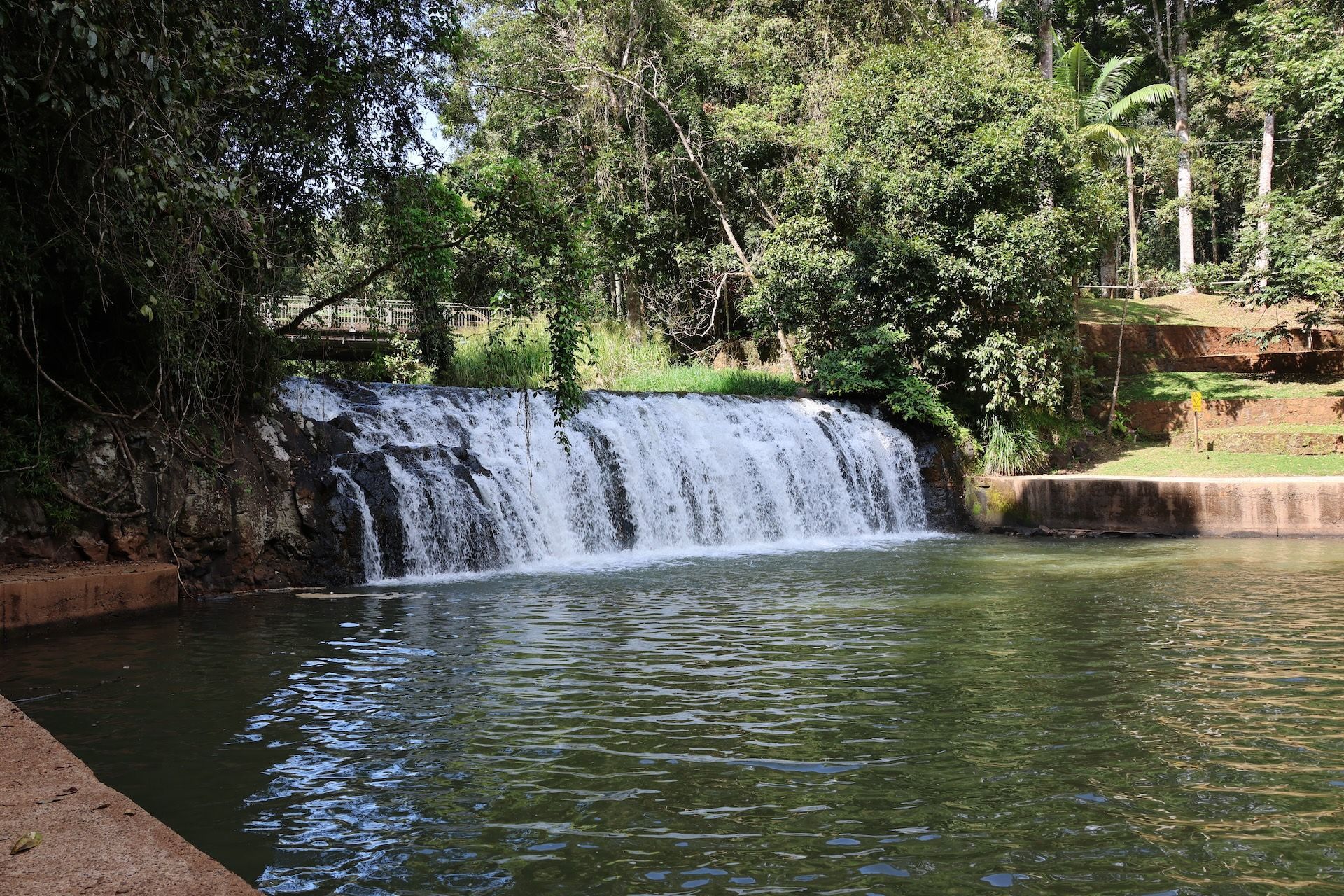 Waterfall cascading into a pool surrounded by trees — FNQ Smoke Alarms & Maintenance in Malanda, QLD