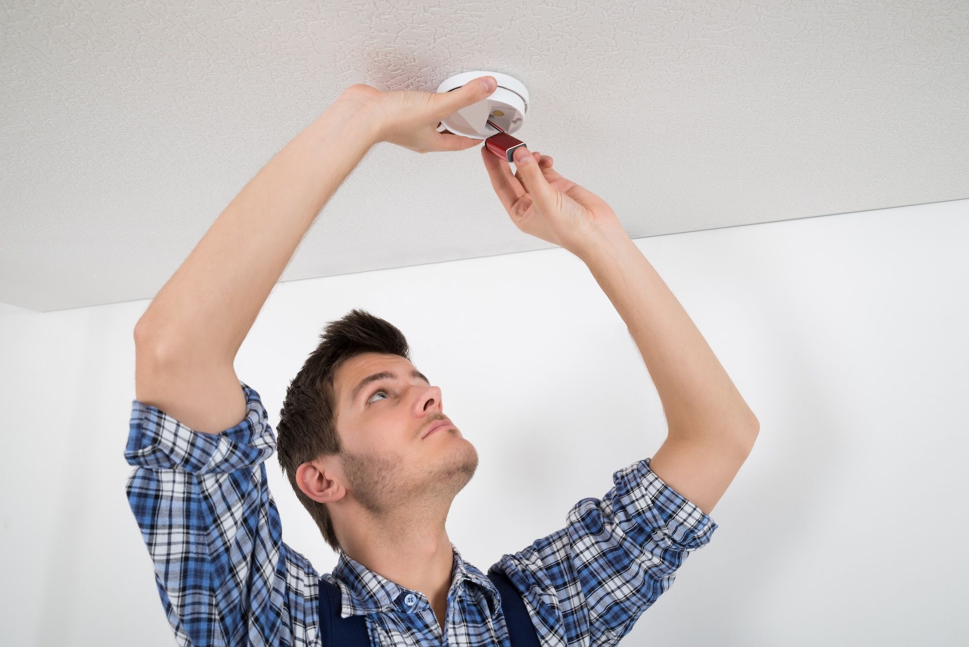Man in Blue Plaid Shirt Installing a Smoke Detector — FNQ Smoke Alarms & Maintenance in Mount Sheridan, QLD