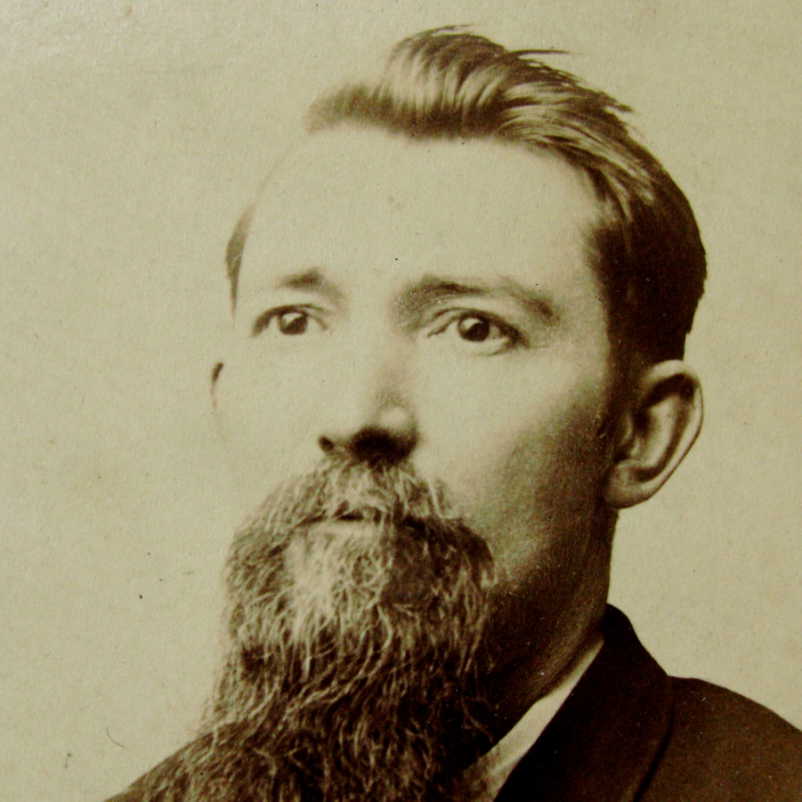 Man with a long beard and mustache, looking to the side.