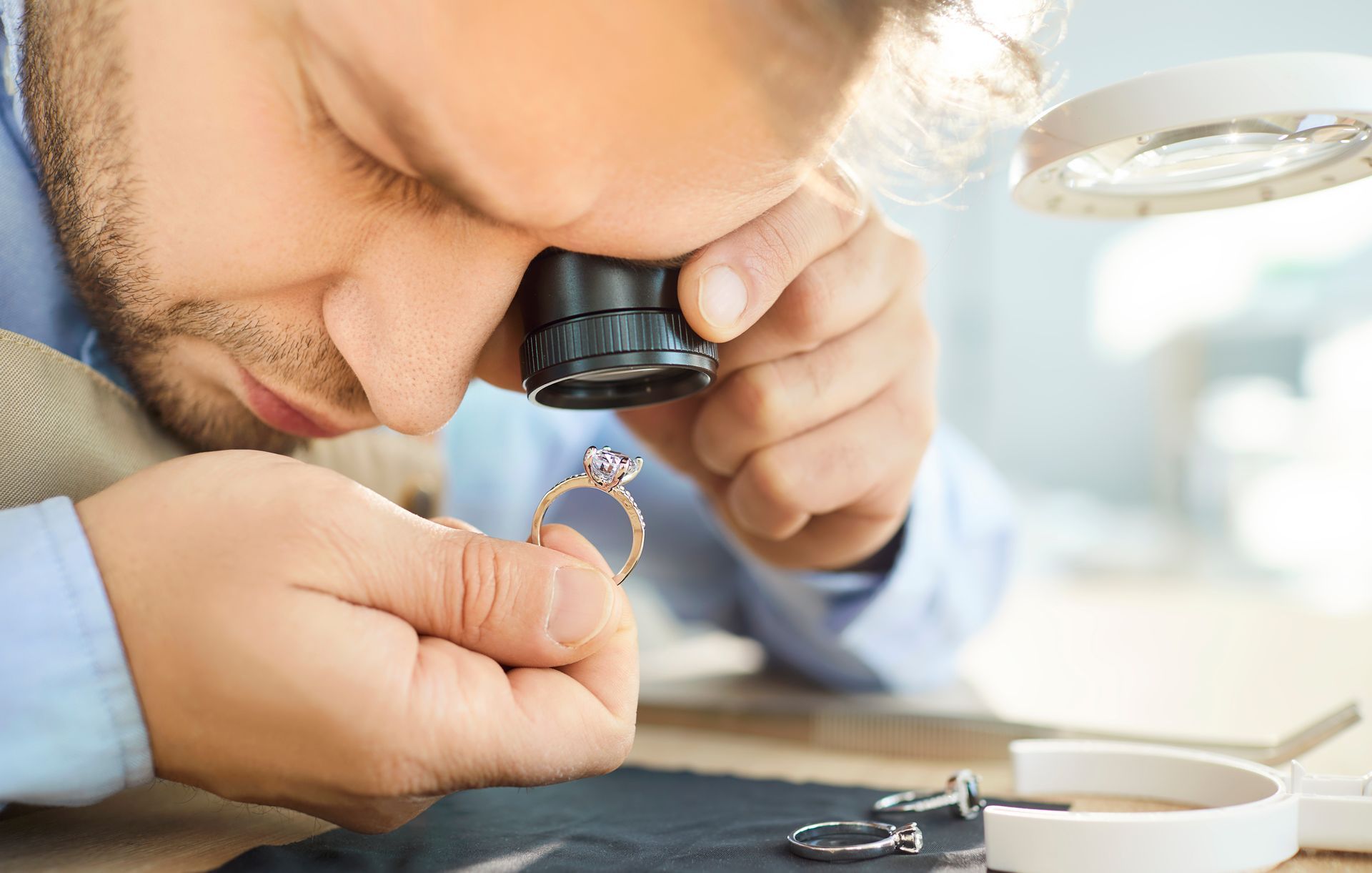 Close-up of a valuer with a loupe performing a jewellery valuation service on a ring.