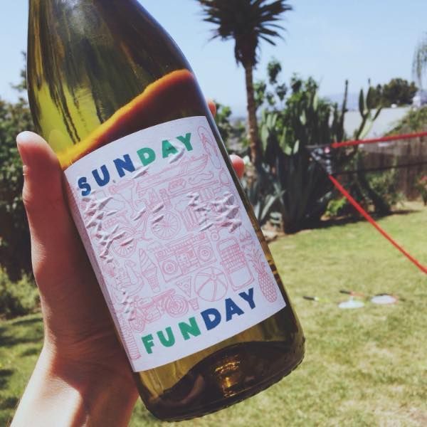 A hand holds a wine bottle labeled 
