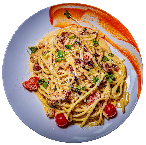 Creamy spaghetti topped with cherry tomatoes, herbs, and breadcrumbs, plated with a decorative smear of red sauce.