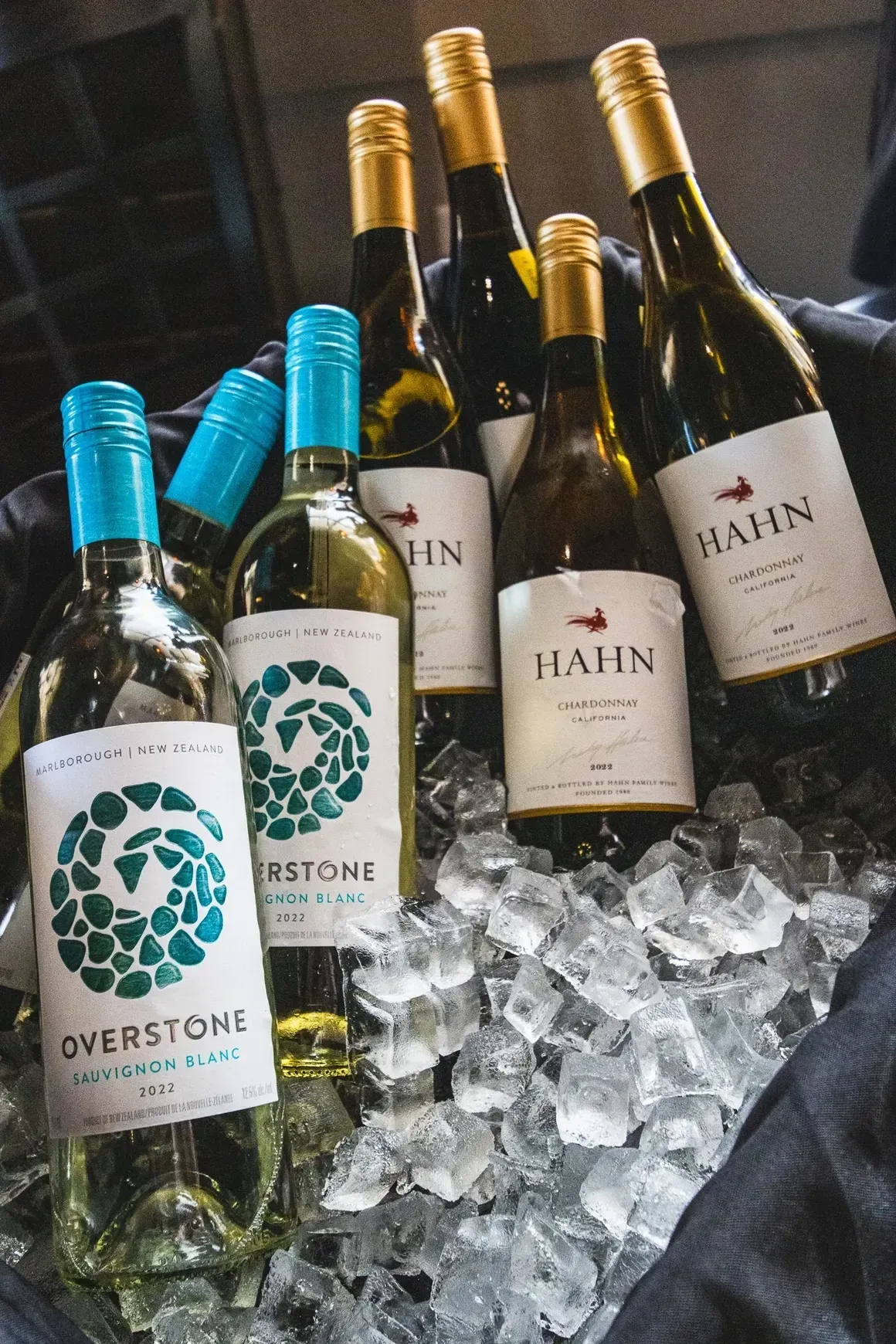 Bottles of Overstone and Hahn wine chilled in a bucket of ice cubes.