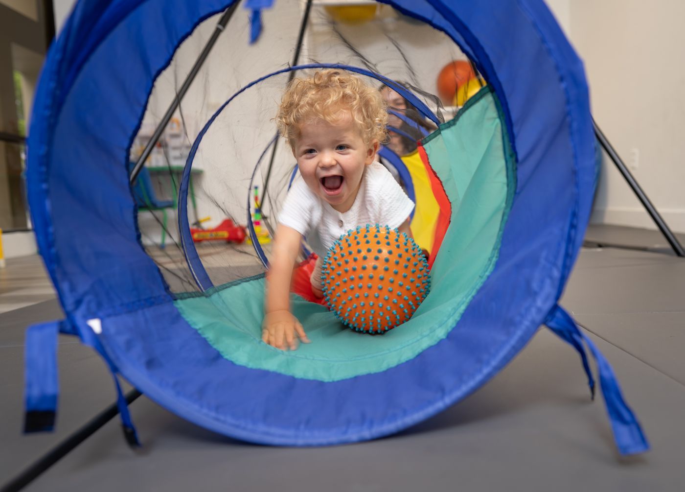A young boy is playing with a ball in a tunnel.