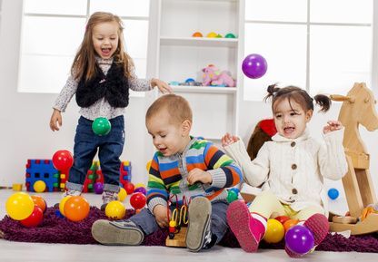 Three children are playing with toys in a room.