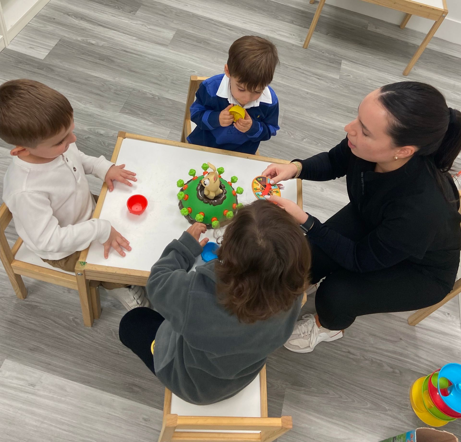 A group of children are sitting around a table playing with toys.