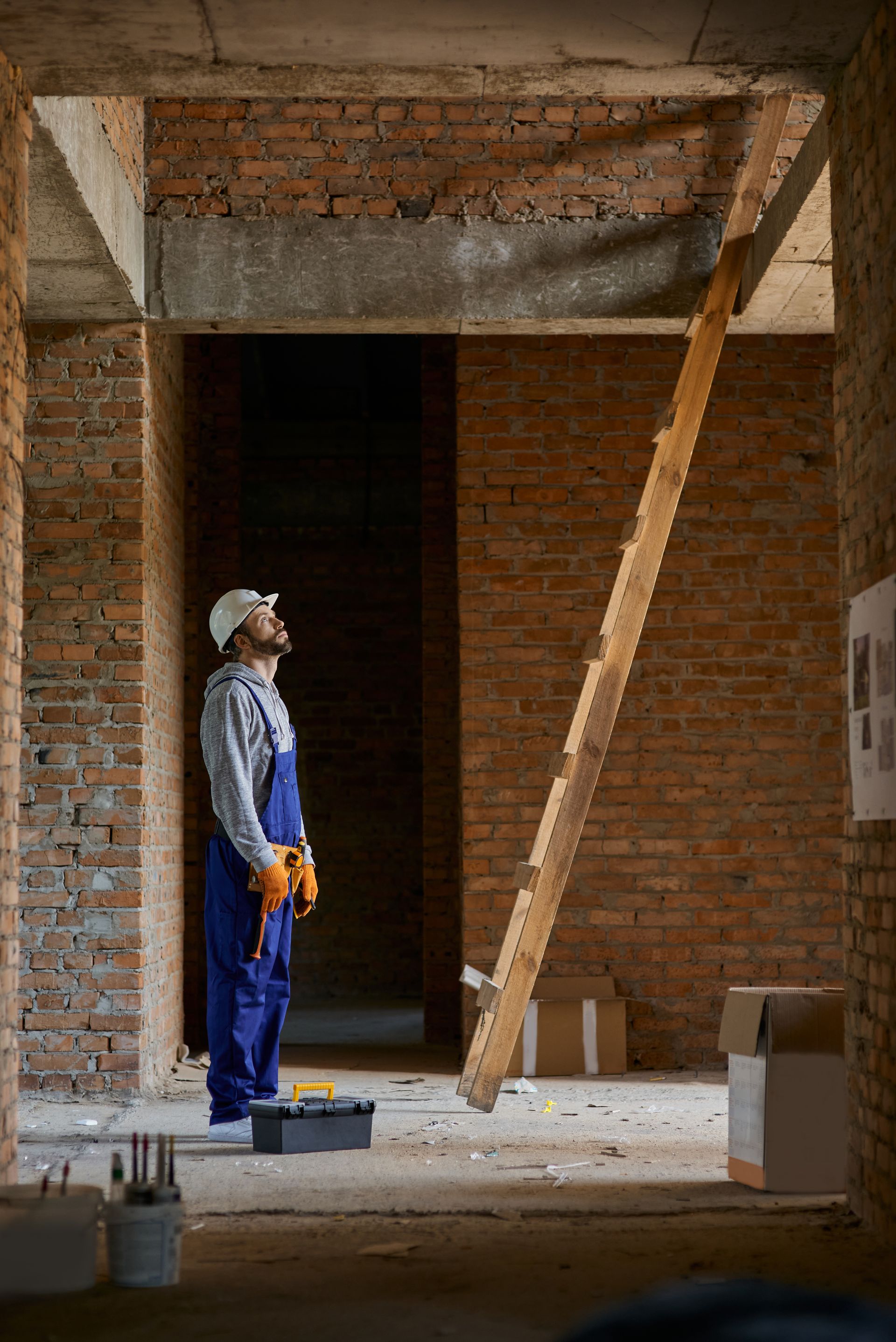 worker in blue overalls next to a ladder