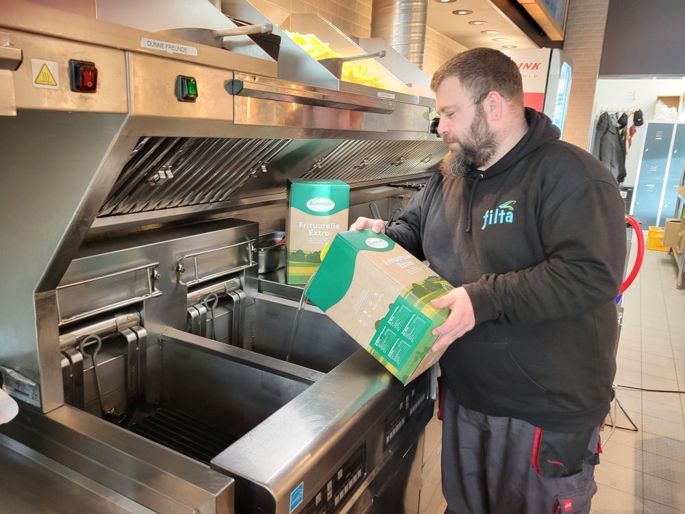 Der Service-Mitarbeiter befüllt die professionell gereinigten Fritteusen mit neuem Qualitäts-Frittieröl.