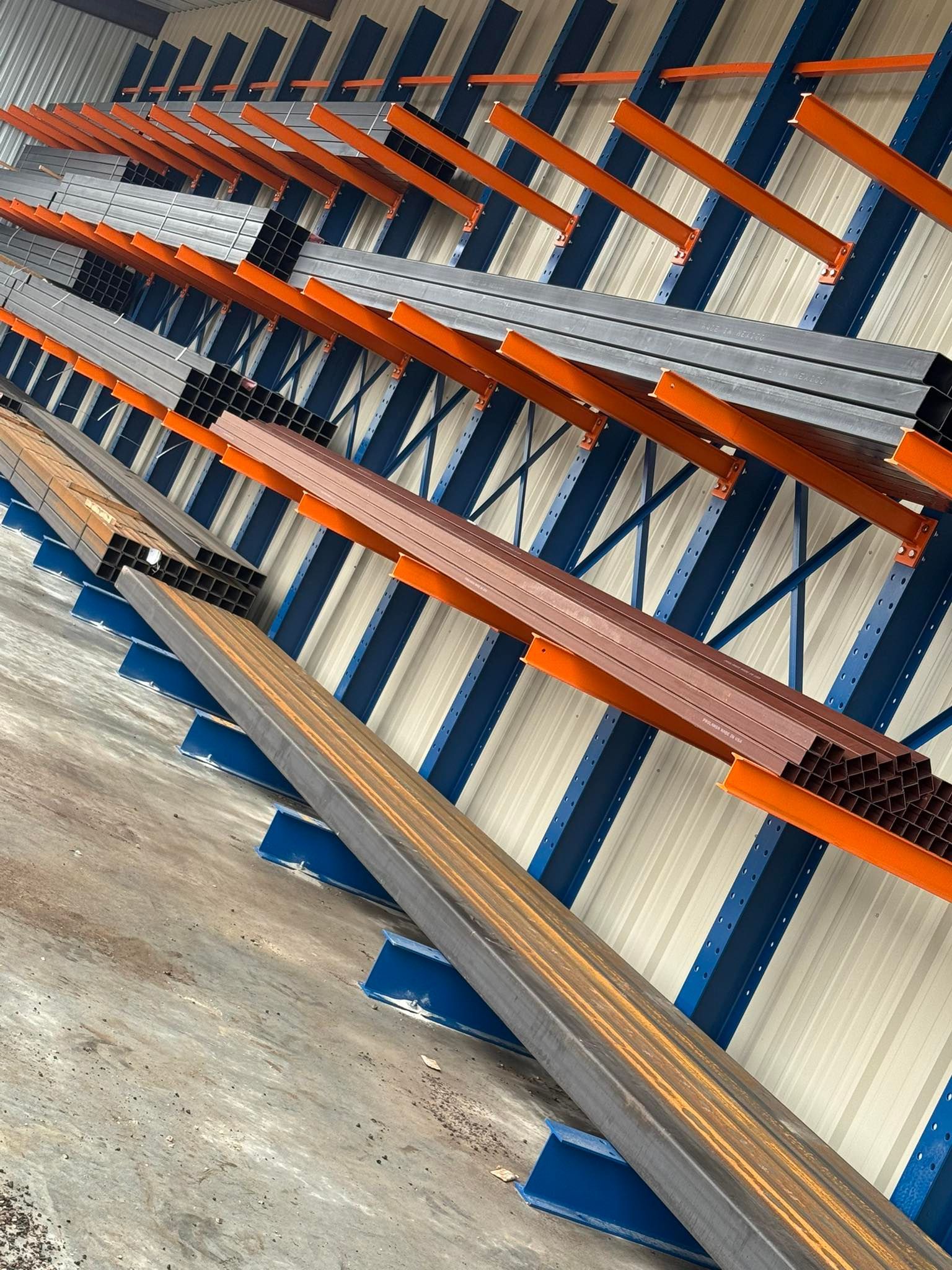 Rows of blue and orange industrial metal shelving in a warehouse aisle