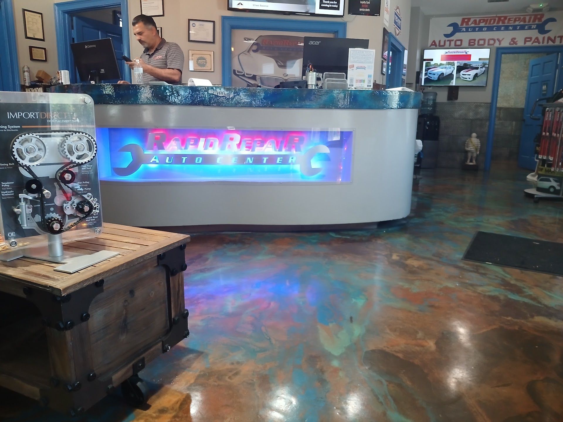 Bright arcade counter with blue neon glow, polished floor, and a small display stand in the foreground | Rapid Repair Auto Center