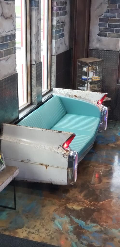 Teal couch in a narrow hallway with exposed brick walls and a colorful floor. | Rapid Repair Auto Center