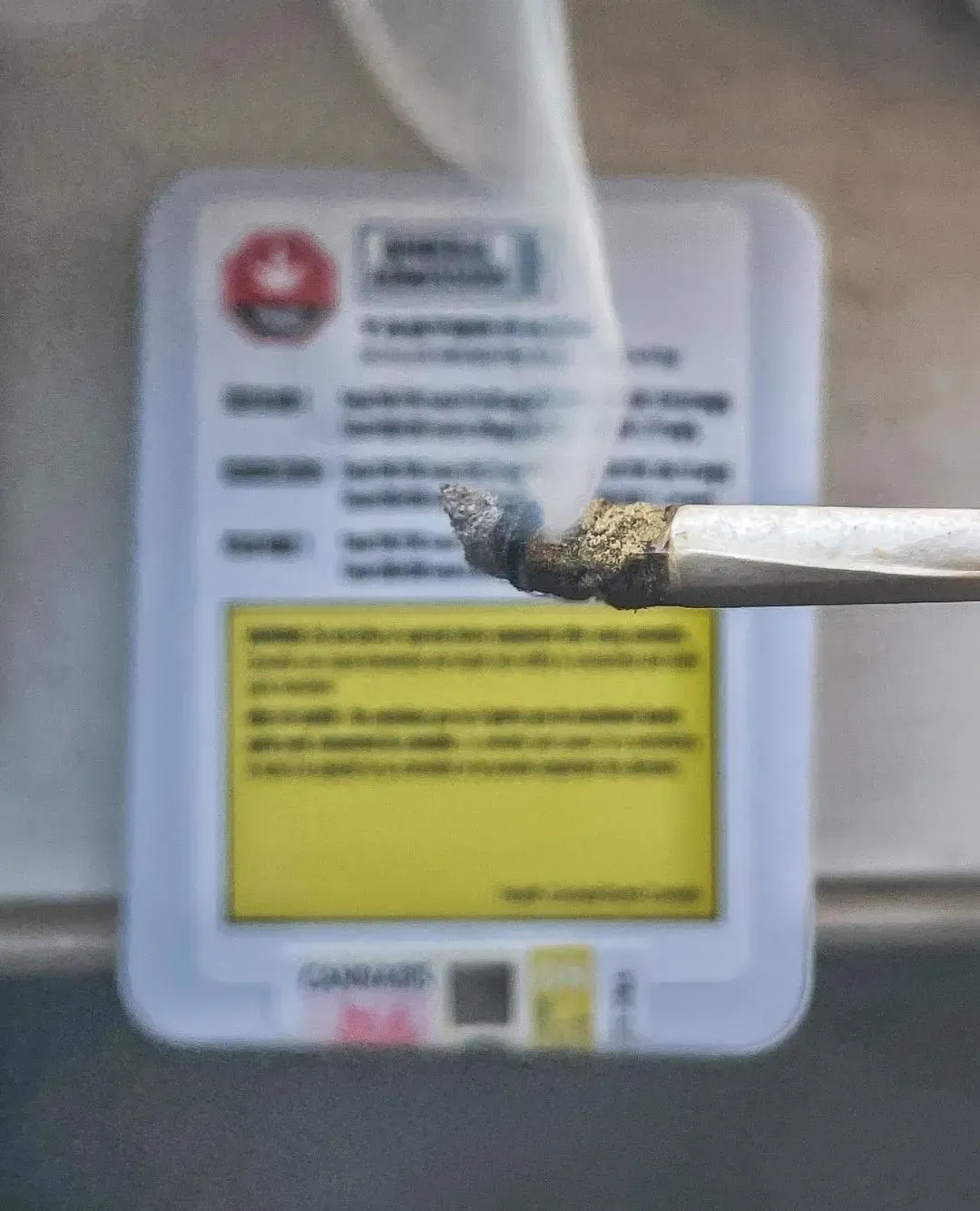 Close-up of a cigarette being extinguished against a white and yellow no-smoking sign.
