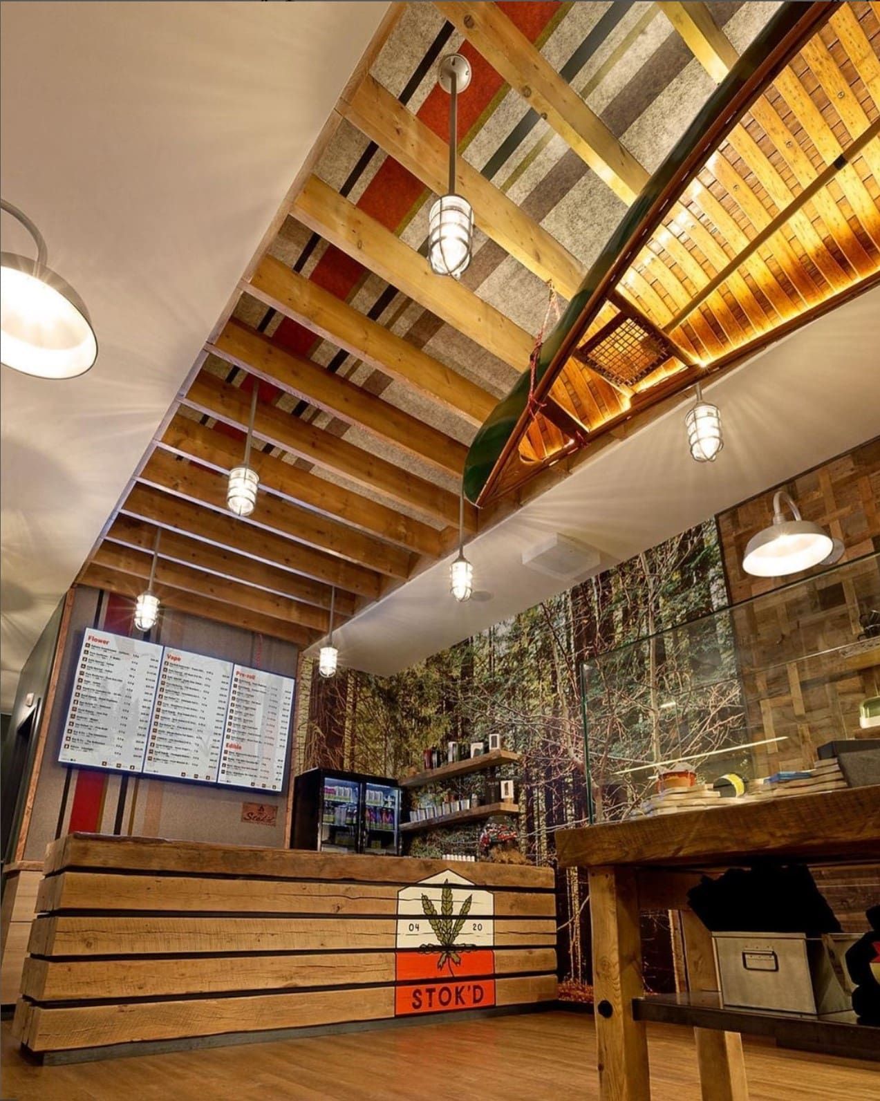 Rustic café interior with wooden tables, hanging lights, and a menu board behind the counter