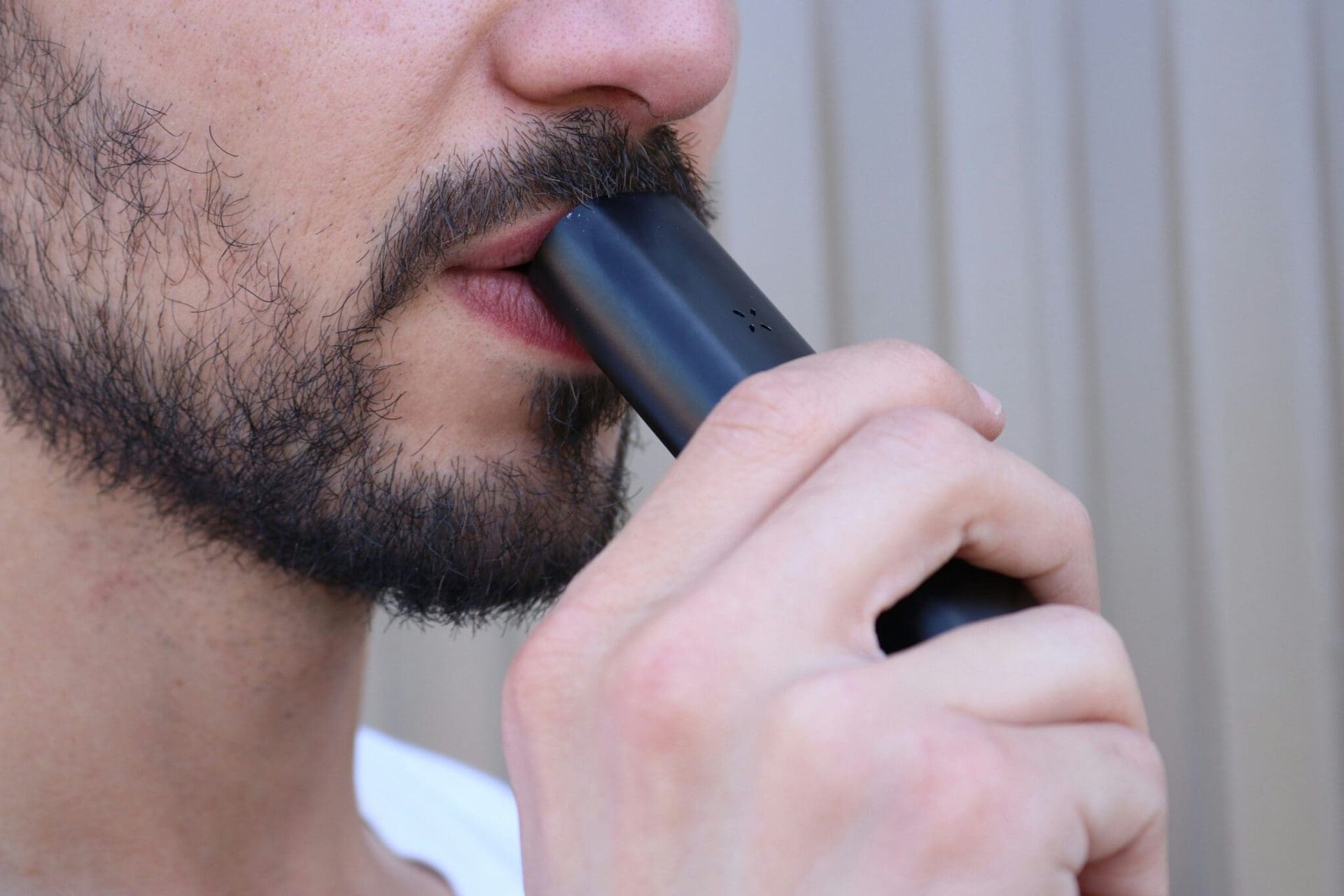 Close-up of a person using a black nasal inhaler near their nose and mouth