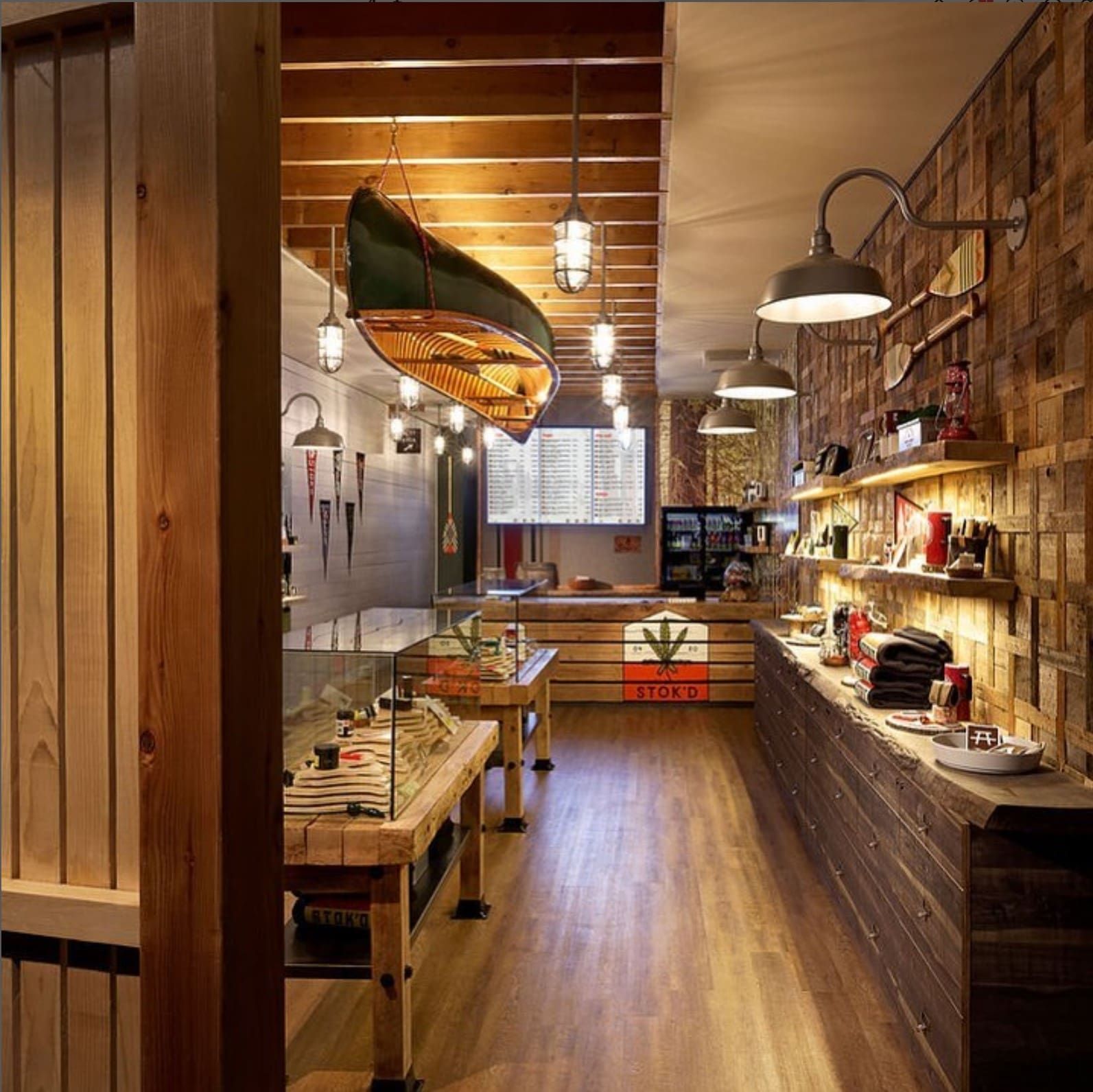 Cozy rustic café interior with wooden walls, hanging lights, tables, and a long counter display