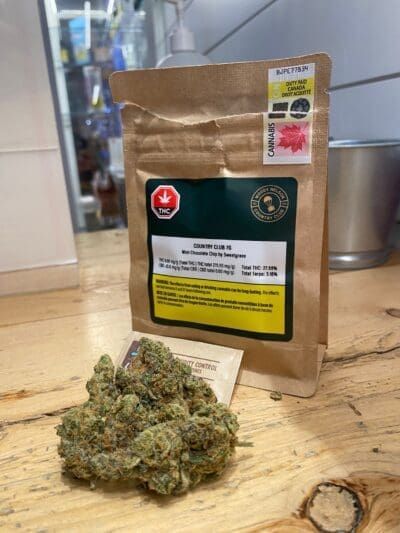 Cannabis bud beside a brown resealable pouch on a table indoors