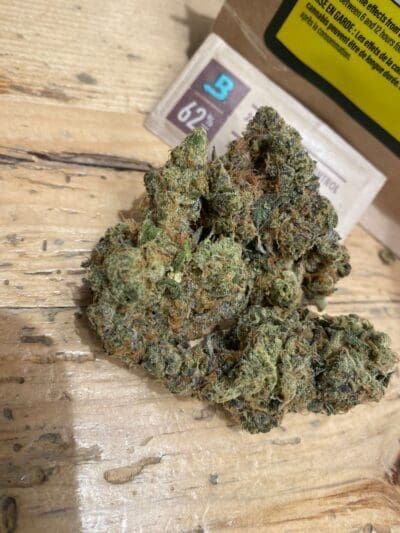 Close-up of cannabis buds on a wooden surface, with a small numbered label behind them