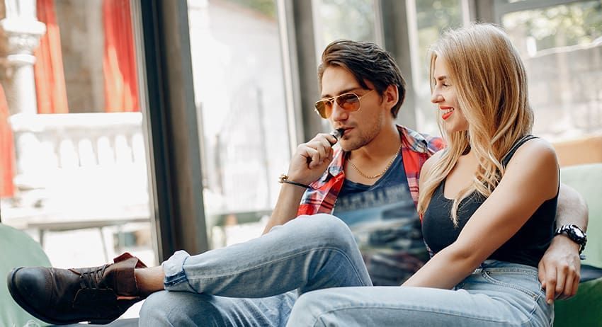 Two people lounging on a couch, one holding a drink, in a bright modern room