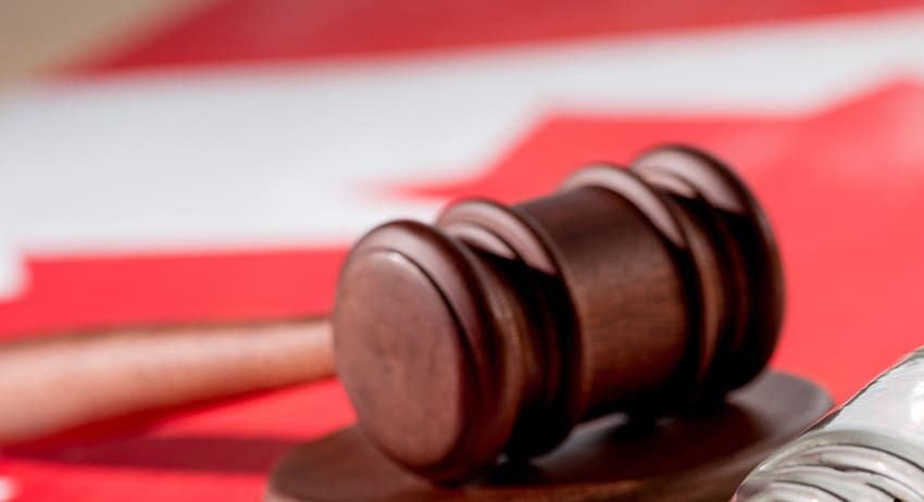 Judge’s gavel on a red background with a blurred American flag behind it