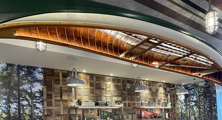 Curved copper ceiling over a cafe/bar interior with hanging lights and shelves of bottles and jars
