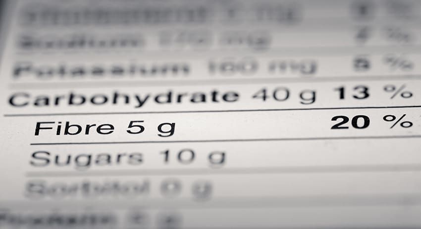 Close-up of a blurry nutrition label showing carbohydrates 40 g, fibre 5 g, and sugars 10 g.