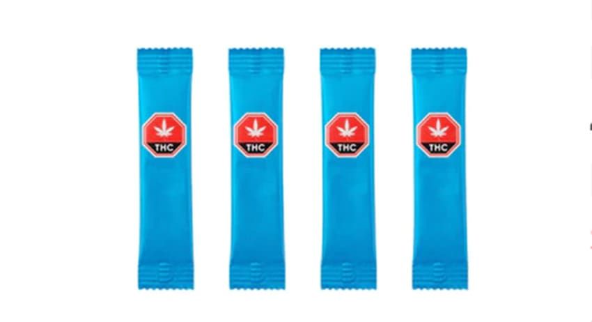 Four blue vertical sachets with red circular labels on a white background