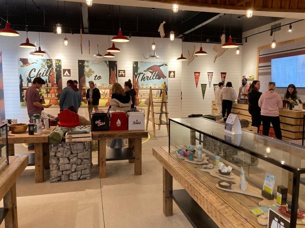 Bright retail shop with people browsing shelves and display tables under hanging lights