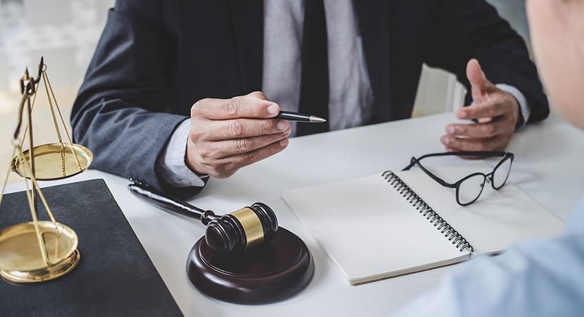 Lawyer at desk with gavel, scales of justice, and eyeglasses during a meeting