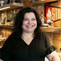 Smiling woman in a black blouse standing in a warm wooden shop