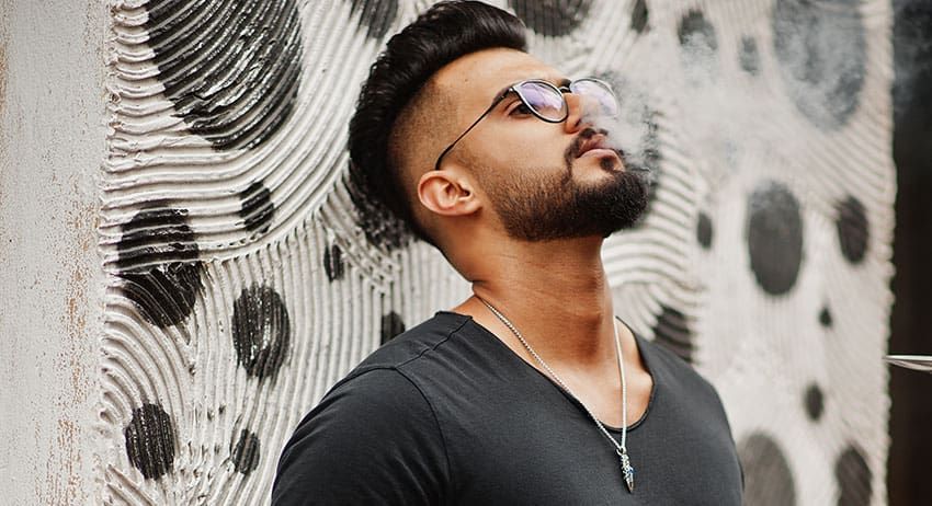 Man in glasses and black shirt looking upward beside a black-and-white patterned wall