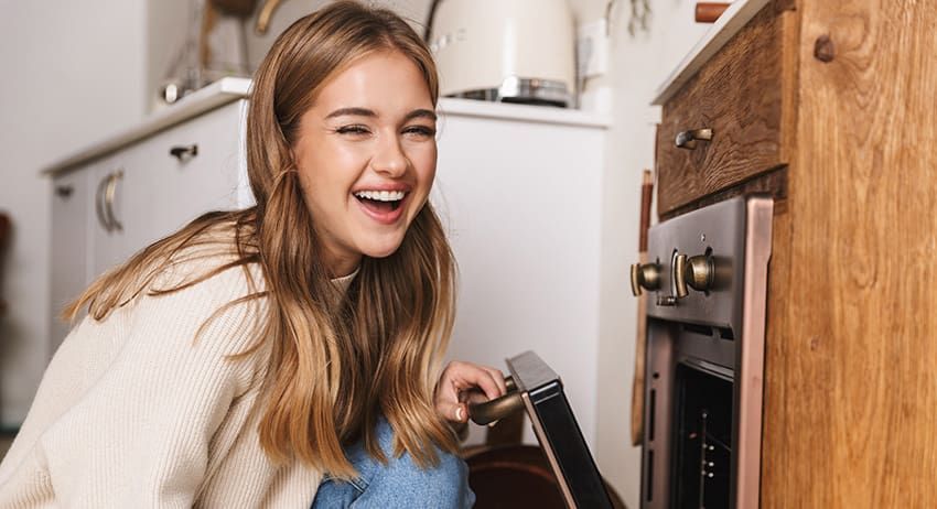 Woman smiling while opening a built-in oven in a kitchen