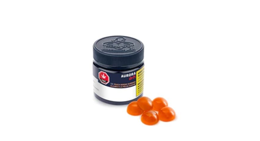 Black bottle of cough syrup beside four orange lozenges on a white background