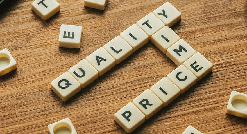 Wooden letter tiles spelling quality and price on a wooden table