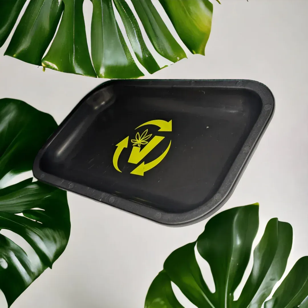 Black rectangular tray with yellow recycling symbol, surrounded by green leaves