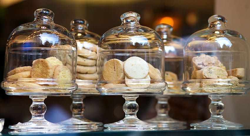 Glass domes displaying assorted cookies on a dessert counter