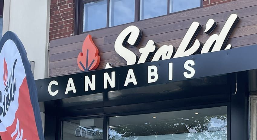 Stok’d Cannabis storefront sign with red leaf logo on a brick building