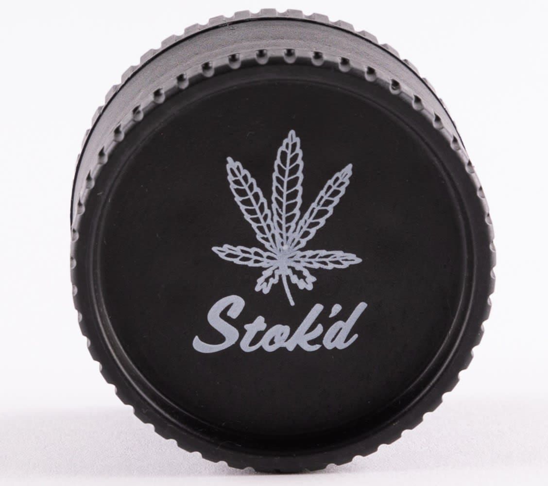 Black cannabis grinder with the Stok'd logo on top, placed on a white background