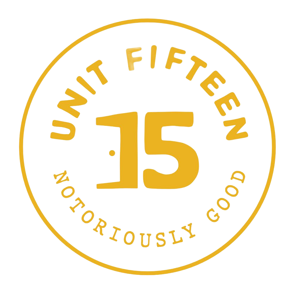 Unit Fifteen logo in gold, with large “15” and the words “Notoriously Good” in a circle.